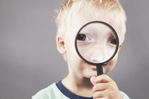 boy child looking through a magnifying glass