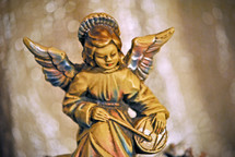 Figurine of an angel seated on the rocks playing a drum; a Christmas decoration.