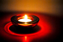 One single votive light in a red glass holder.