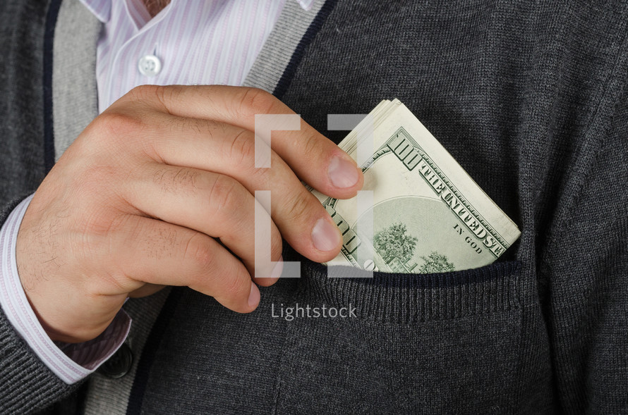 Hand putting folded hundred dollar bills in a pocket.