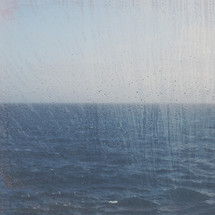 looking through wet window at the oceans horizon