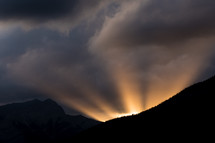 rays of light at sunrise behind a mountain 