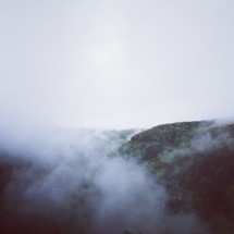 Clouds and mist over tree-covered mountains.