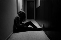 teen girl with her head held down sitting in a hallway 