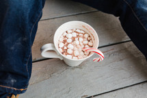 child and a mug of hot cocoa with a candy cane 