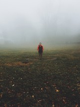 man standing in a field on a foggy morning 