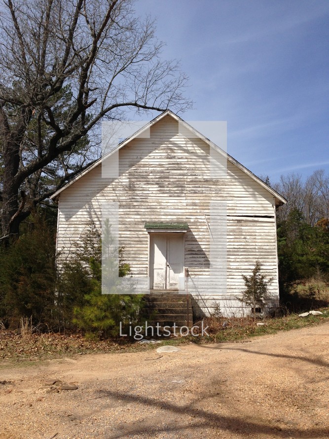 Old church building on a dirt road.