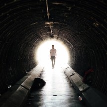 man walking through a wet tunnel 
