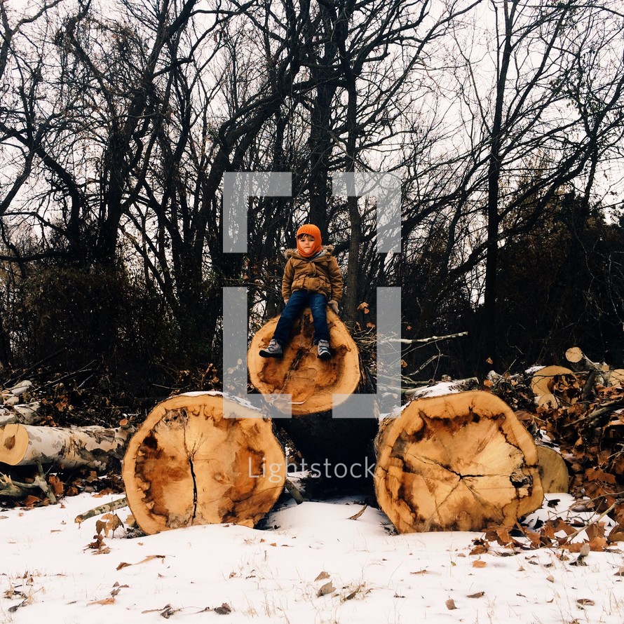 child on cut logs 