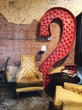 An eclectic room with vintage chairs and a large red number two.