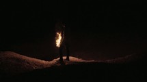 a man standing in darkness holding a glowing torch 