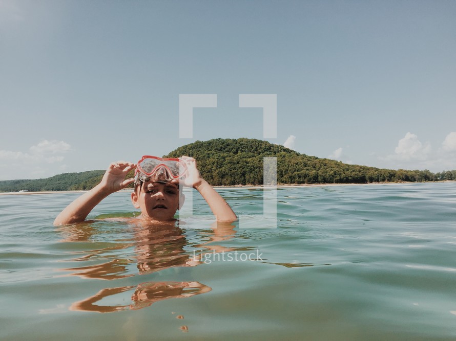 a boy with goggles in a lake 