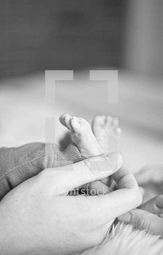 father holding a newborns tiny feet