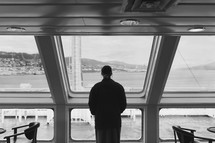 a man looking out at a marina through the windows of a restaurant 