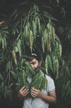 a teen boy hiding in leaves on a tree 