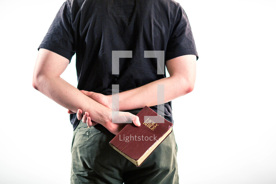 a man holding a Bible behind his back 