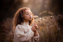 a girl holding a dried brown flower 