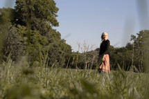 A teen girl standing in green grass 