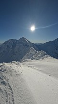 Vertical video of Frozen winter alps snowy mountains in sunny day with blue sky, adventure mountaineering background
