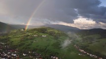 Aerial view of rainbow over green rural countryside in sunny rainy evening