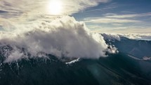 Time lapse of clouds rolling over snowy mountains.