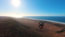 Freedom paragliding flying over dry country in African Morocco ocean coast in sunny summer, Adrenaline Adventure Sport
