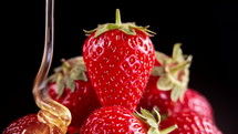 Honey being drizzled over ripe strawberries