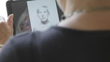 elderly woman looking at old photographs on a tablet 