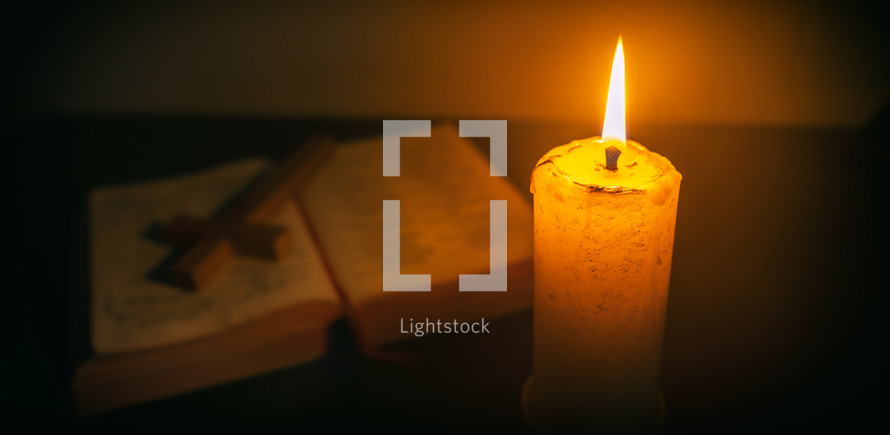 Candle on wooden table with the Bible and cross in the night. worship prayer and bible study concept.