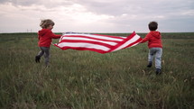 Cute little boys - American patriot kids running with national flag on open area field. USA, 4th of July - Independence day, celebration. US banner, memorial Veterans Day, election, America, labor.