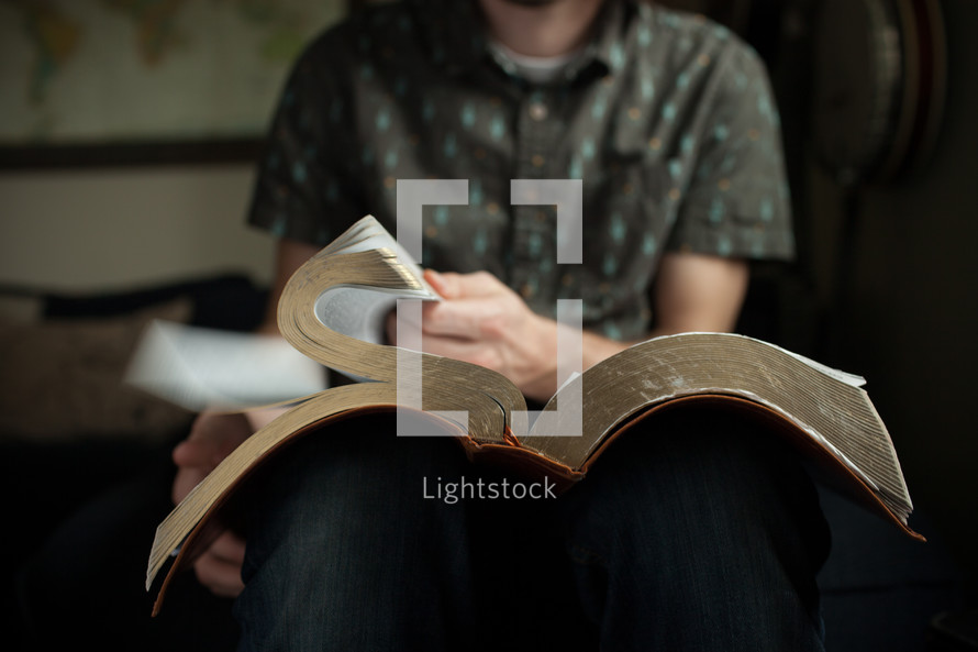 a man sitting reading an oversized Bible 