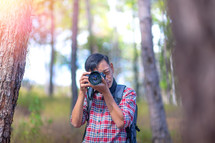 a man in a forest holding a camera 