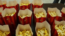 Bags of popcorn lined up at a movie or an event
