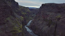 Fly backwards in dark river canyon in volcanic Iceland nature