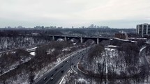 Aerial view of Prince Edward Viaduct in downtown Toronto on a winter day. Aircraft flying over Don Valley Parkway with moderate traffic. Drone moving forward while doing a slight orbit movement. 