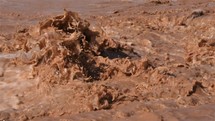 Slow motion of brown water rapids splashing on flooded river after storm rain
