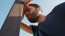 Tired Man Resting On Exercise Pole Outdoors