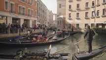 The atmosphere of narrow canals in the city of Venice, with many bridges and small boats parked.