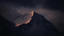 Dramatic mountain summit covered by snow during sunset