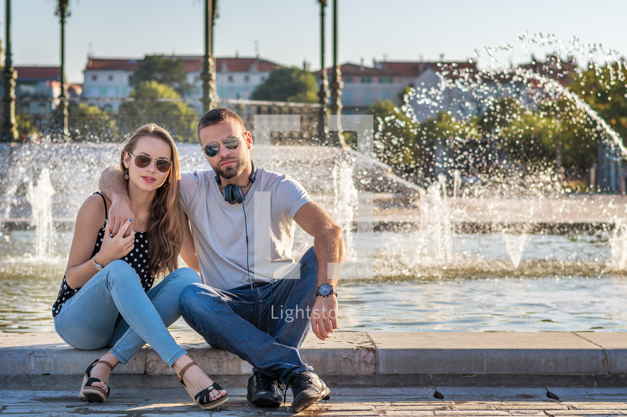 a couple in the city in front of a fountain 