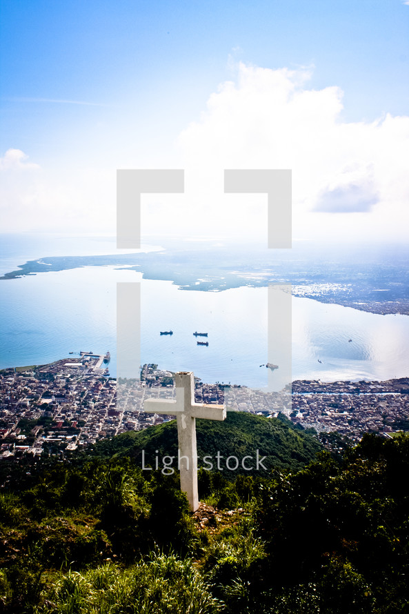 cross on a mountain top above the shore 