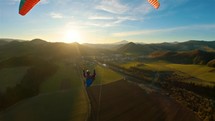 Paragliding flight above green spring countryside nature at golden sunset flying freedom adrenaline adventure
