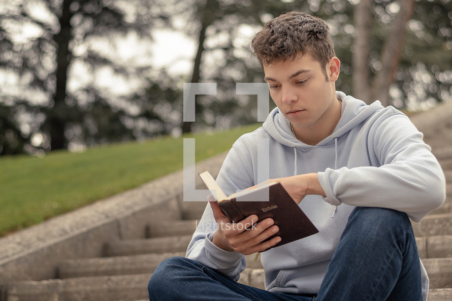 Christian worship and praise. A young man is praying and reading the bible in the evening