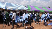 children moving chairs under a tent for a worship service 