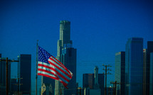 American flag in front of city sky scrapers