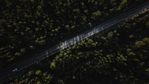 Aerial top down view of cars driving on a highway surrounded by trees