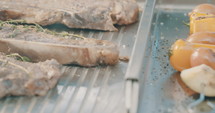 Close up slow motion shot of meat on a grilling plate in an outdoor luxury kitchen.