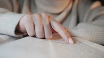 Close up of a woman's finger as she reads the Bible.