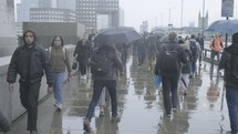 Commuters walking in the rain at rush hour on London Bridge, London