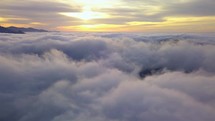 Fly above clouds in misty nature heaven landscape at golden sunrise Aerial view

